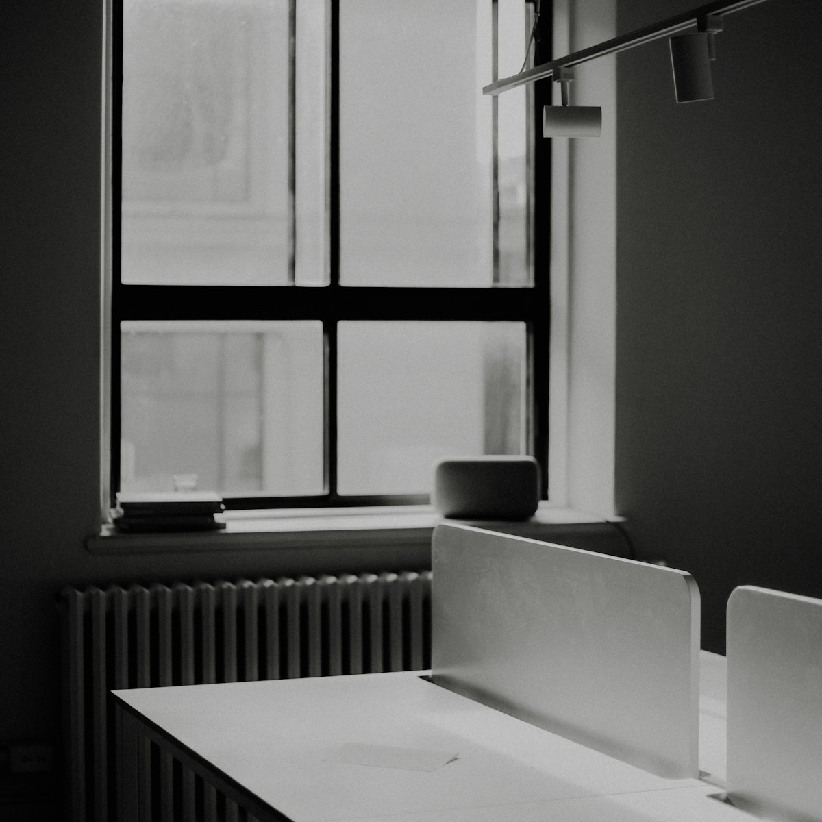 A quiet desk by a tall window in a black-and-white office