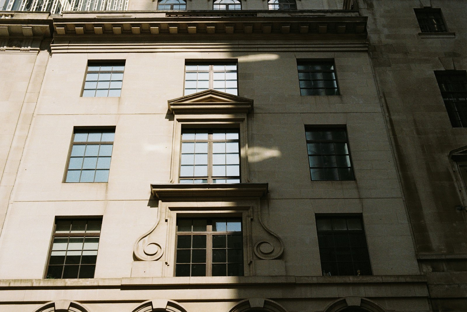 Stone facade of a classical European building with tall windows in soft side light