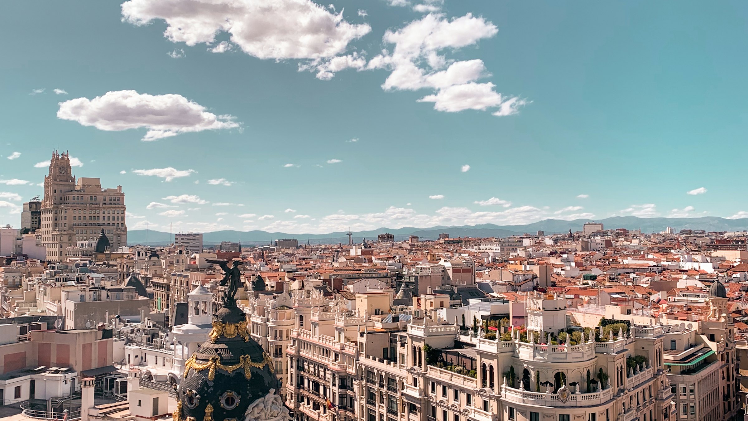 Rooftops of central Madrid seen from above, with the Metrópolis building dome in the foreground